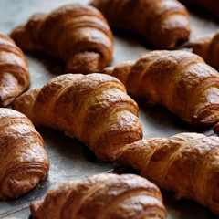 close up of freshly baked crusty croissant on buffet line background. A tray with fresh croissant bread puff pastry at a local bakery