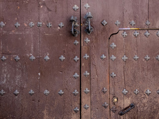 Old wooden gate fixed with   brass rivets in Cordoba, Andalusia, Spain.