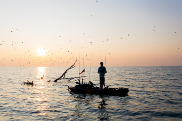 Fototapeta premium Young Man Kayak Fishing at Sunrise in Canada