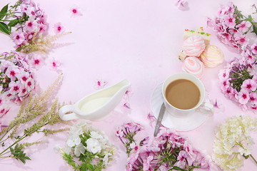 Colorful flowers of pink phlox, cup of coffee and marshmallow with pastilla on a wooden table, top view with place for text, flat lay-out, selective focus. Pink flowers on wooden background