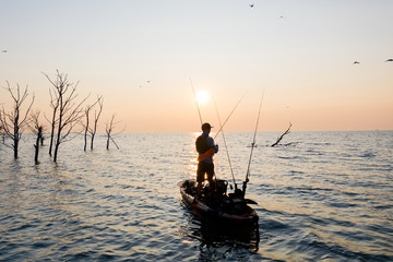 Fototapeta premium Young Man Kayak Fishing at Sunrise in Canada