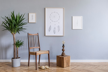 Stylish bohemian interior design of living room with retro chair, rattan slippers, wooden cube,...