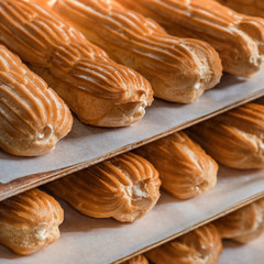 close up traditional eclair. Process of greasing unbaked eclairs with eggs on baking pan. Cooking french dessert. A tray with fresh bakery products puff pastry at a local bakery