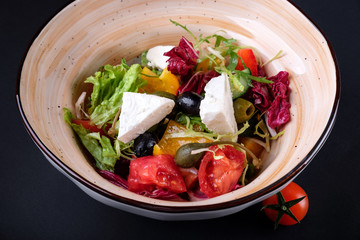Closeup traditional greek salad with fresh vegetables, feta cheese, olives and olive oil in a bowl. Top view. Rustic style. Selective focus. Healthy food.