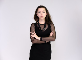 Portrait on white background of a pretty slim beautiful fashionable adult girl with beautiful brunette hair in a black dress. Standing talking demonstrating different poses and emotions