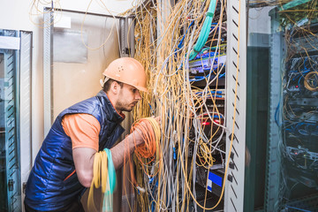 A technician commutes many trouble-free wires in the data center server room. Engineer repair...