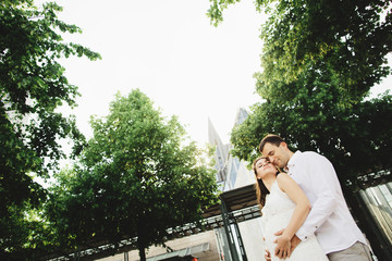 Young couple walks around the city. A man gently embraces his pregnant wife. Germany, Leipzig