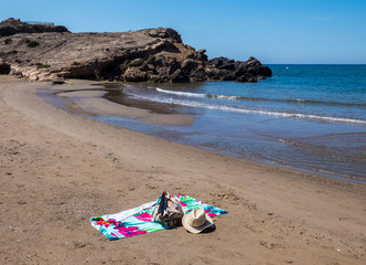Fototapeta na wymiar Empty beach in Costa Calida , hat, a beach bag, and a towel lie on the beach