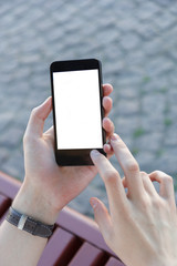 Casual young man using smart phone sitting on bench in city