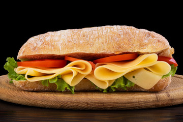 Ciabatta sandwich with lettuce , prosciutto and  cheese on wooden board