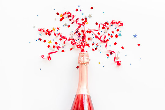 Champagne bottle with colorful party streamers for celebration on white background top view