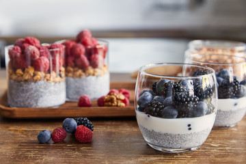selective focus of yogurt with chia seeds, raspberries, blueberries and blackberries in glasses in kitchen