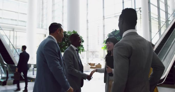 Business people interacting with each other in the lobby at office 4k