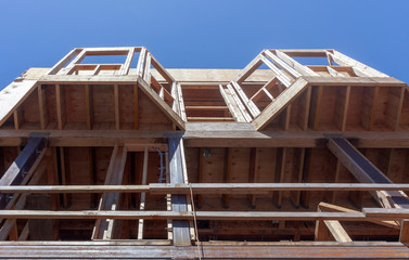 Looking up at wooden framework of urban apartment building bay windows.