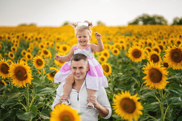 Father playing and spinning with his daughter in the field of sunflower.