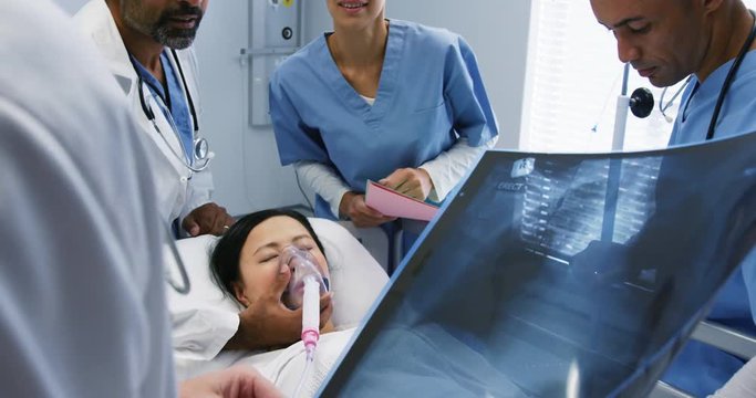 Doctors in consultation over patient in hospital bed 4k