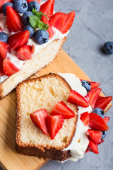 Buttercream berry pound cake with slice, colorful fruits and berries on top