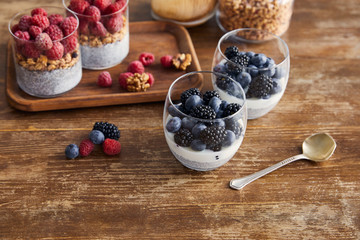 breakfast with oat flakes, yogurt with chia seeds and berries on wooden tray on table