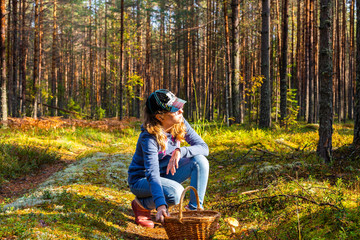 Teen girl gathers mushrooms for a walk in the summer or autumn forest.
