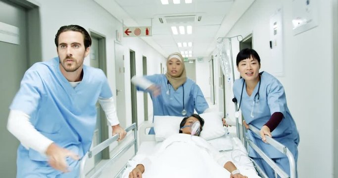 Three healthcare workers urgently pushing hospital bed down corridor in an emergency 4k