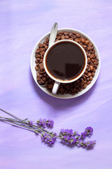 A cup of coffee and lavender flowers on a lilac background. Gentle, summer, coffee design with place for text.