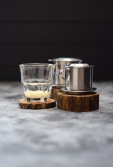 Condensed milk in glass ready for making Vietnamese drip coffee in coffee maker phin on wood slabs minimalist style on dark background