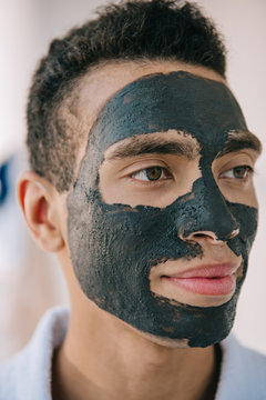 Portrait Shot Of Handsome Man With Grey Clay Mask On Face Looking Away