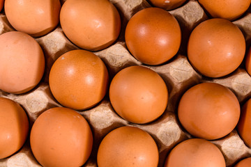 Pile of the hen eggs in paper tray on wooden table. Top view