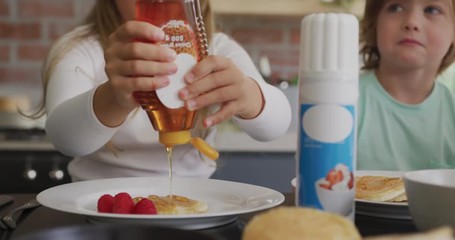 Girl putting honey on pancake at dining table in a comfortable home 4k - Powered by Adobe