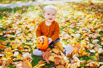 Adorable little girl sitting on the grass with Halloween bucket