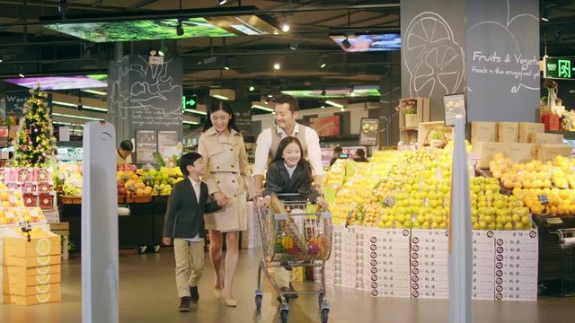 happy asian family with two children grocery shopping in supermarket