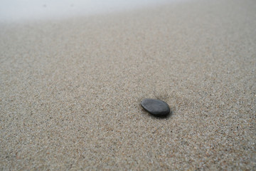 Fototapeta na wymiar The dark stone on the sand