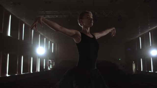 Arts and entertainment in theatre with female classic dancer in tutu, standing behind the scenes and looking at stalls.