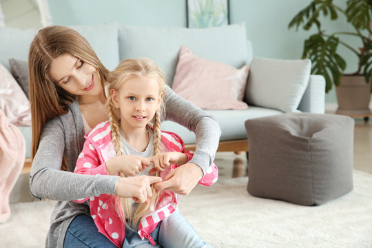 Little deaf mute girl and her mother using sign language at home