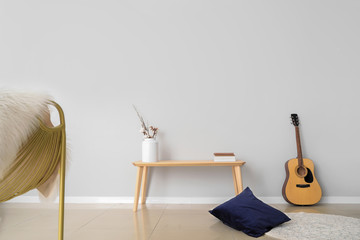 Table with guitar near light wall in room