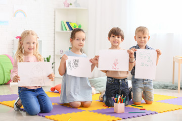 Cute little children with pictures in kindergarten