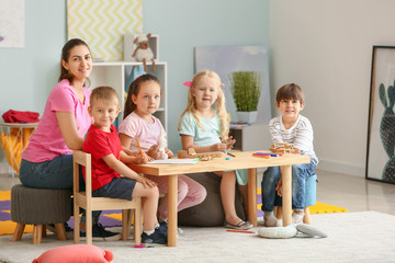 Nursery teacher with cute little children in kindergarten