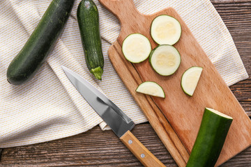 Fresh zucchini, knife and cutting board on wooden background