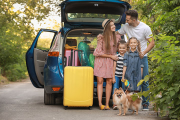 Happy family near car with packed luggage outdoors