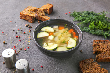 Bowl of tasty soup with bread and spices on grey background