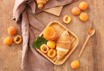 Plate with tasty apricot jam and croissant on wooden table