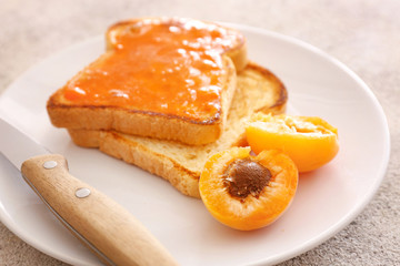 Fototapeta na wymiar Tasty apricot jam with bread slices on plate, closeup