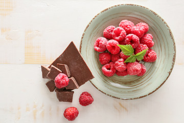 Fresh raspberries with chocolate on white wooden table