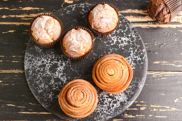 Tasty muffins with buns on wooden table