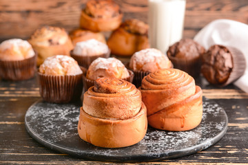 Tasty buns with muffins on wooden table