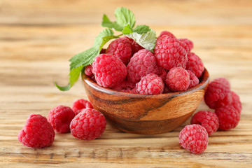 Bowl with sweet ripe raspberries on wooden table