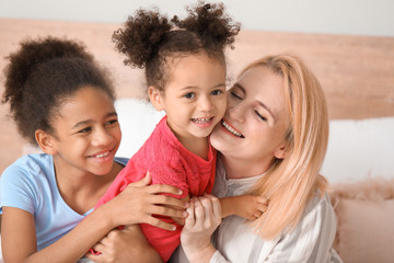 Happy woman with her African-American daughters at home