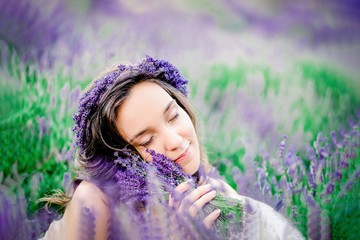 Beautiful girl holding purple violet lavender bouquet on the lavender field. Healthy sleep and aromatherapy concept