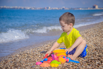 The boy plays on the beach in the toys for the sand. Children's games. Games on the beach. Galichny beach. Children's toys for sand. The baby is playing