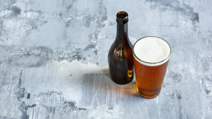 Glass of light beer on white stone background. Cold alcohol drink and bottle are prepared for a friend's party. Concept of drinks, fun, food, celebrating, meeting, oktoberfest.